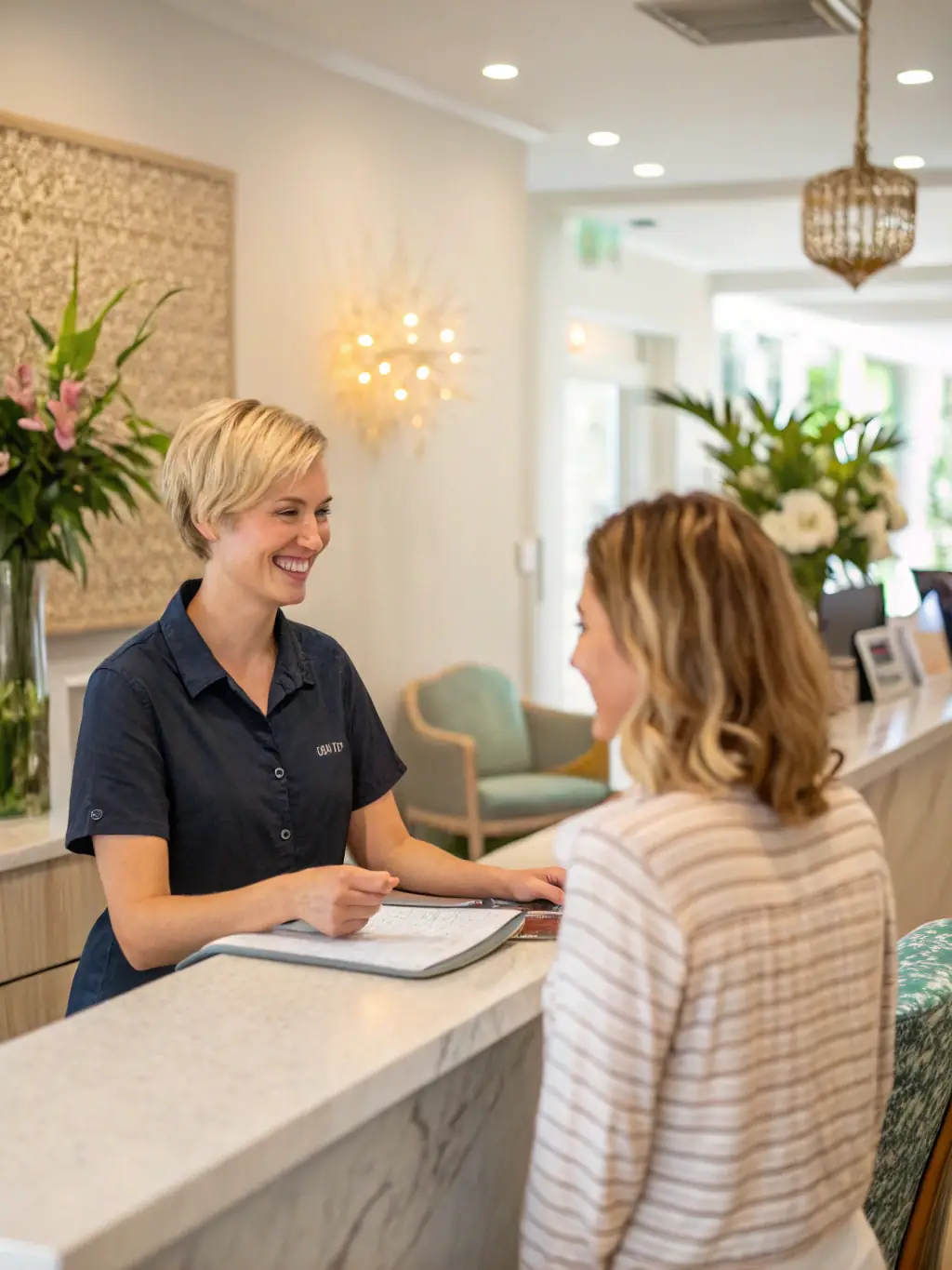 A friendly receptionist assisting a client at the front desk of Inspire Salon Suites, creating a welcoming atmosphere.