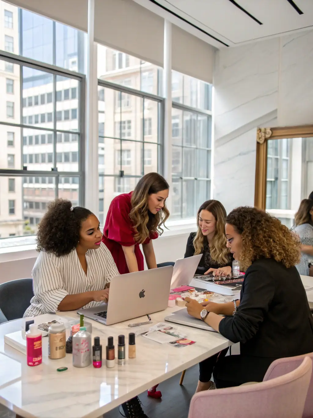 A group of beauty professionals laughing and collaborating in a communal lounge area of Inspire Salon Suites, fostering a sense of community.